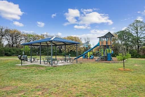 A playground with a blue canopy and a yellow slide.