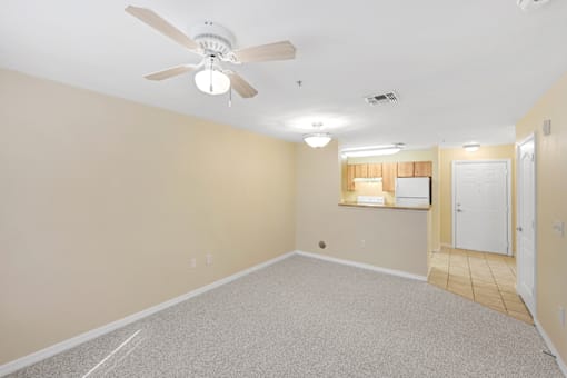 a bedroom with a ceiling fan and a kitchen in the background