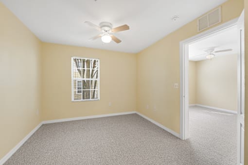 a bedroom with beige walls and a ceiling fan