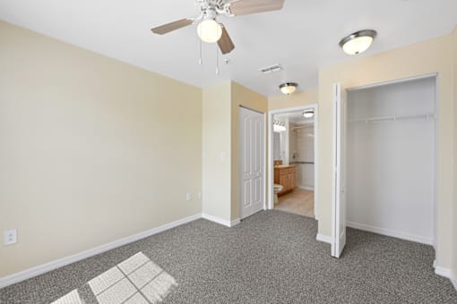 a bedroom with a ceiling fan and a door to a bathroom