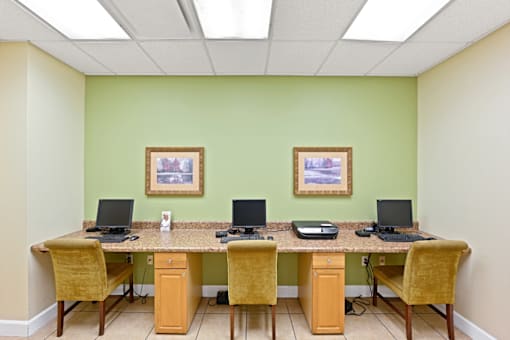 a computer lab with three computers on a long desk