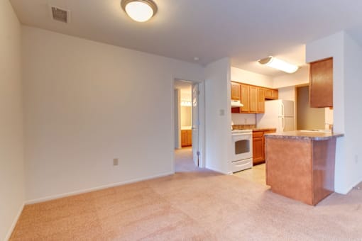 an empty dining room with a kitchen in the background