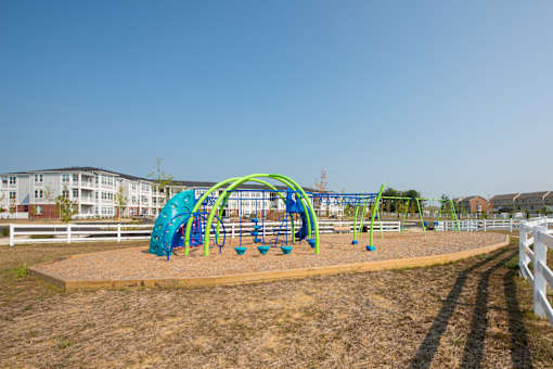 a playground with a blue and green slide in front of a white fence