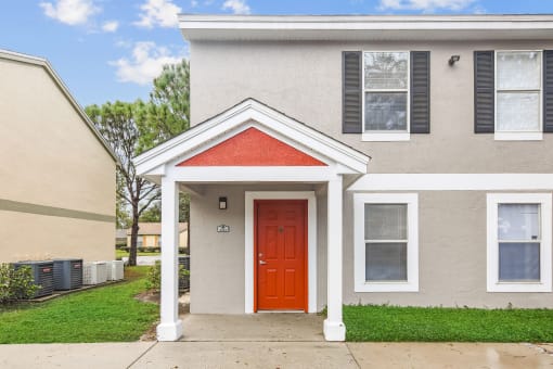 a white house with a red door and a yellow house next to it