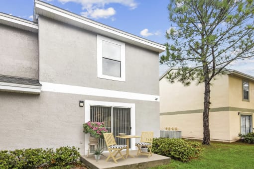 a patio with a table and chairs in front of a house