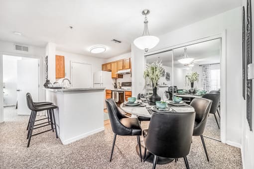 Modeled dining area with a mirrored closet doors adjacent to a galley kitchen with a breakfast bar,
