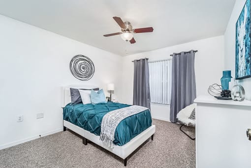 Modeled bedroom with carpet, a ceiling fan, and a window with vertical blinds.