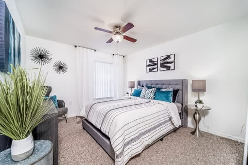 Modeled bedroom with carpet, a ceiling fan, and a window with vertical blinds.