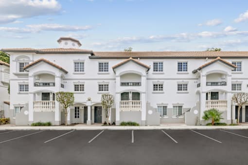 a large white building with balconies and a parking lot