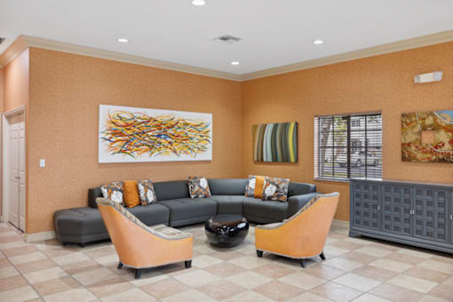 A clubroom with a grey couch and orange chairs.