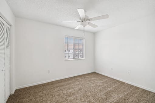 an empty room with carpet and a ceiling fan