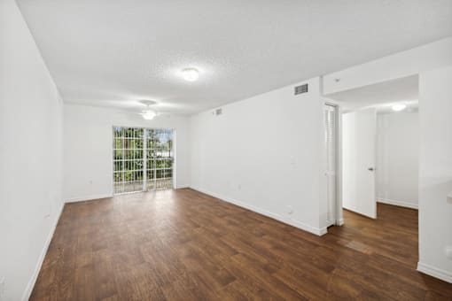 an empty living room with wood flooring and a window