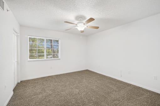 an empty room with carpet and a ceiling fan