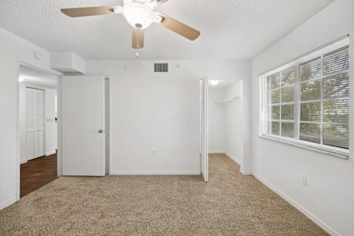 an empty living room with a ceiling fan and a window