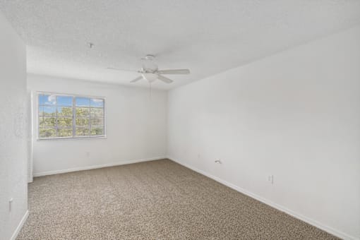 an empty room with carpet and a ceiling fan