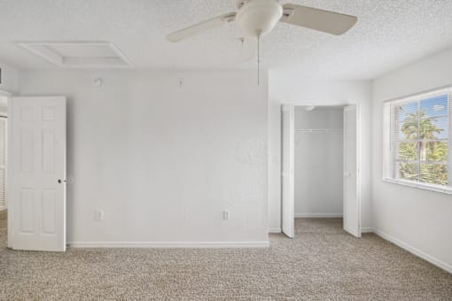 an empty room with white walls and a ceiling fan