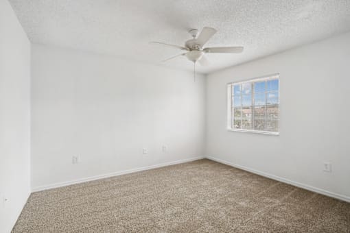 an empty room with carpet and a ceiling fan