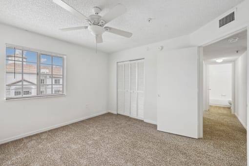 an empty living room with a ceiling fan and a window