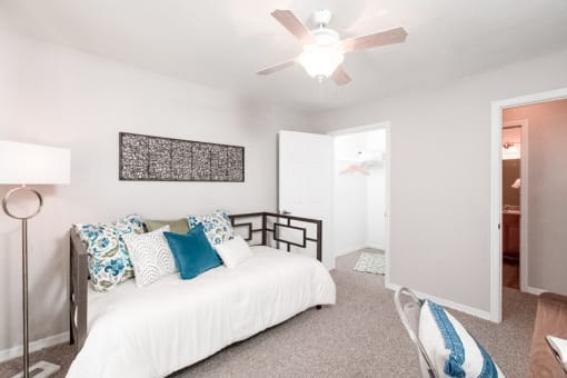 Furnished model apartment featuring a day bed and ceiling fan.
