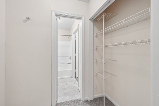 A white closet with shelves and an open door.
