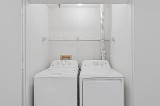 Two white front loading washing machines in a laundry room.