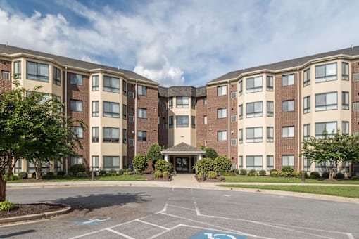 A large apartment complex with a parking lot in front.