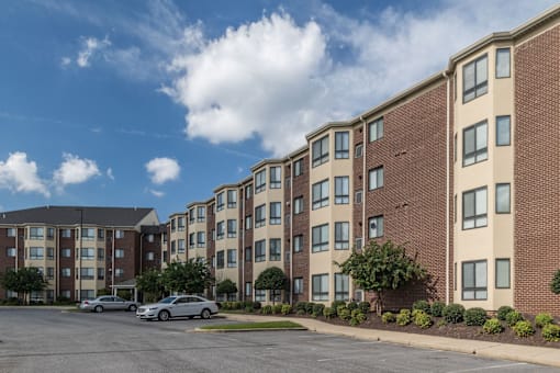 A large brick apartment building with a parking lot in front.