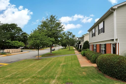 Large grass front yard leading to entrance of apartment buidling.