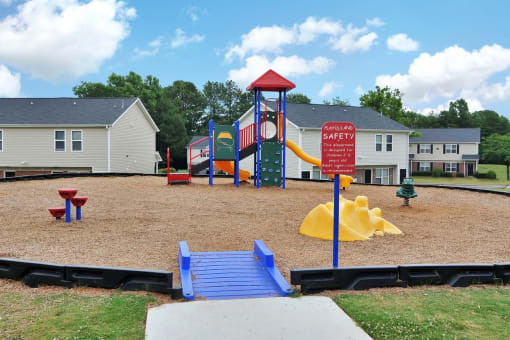 a playground with a slide and monkey bars in a park with houses in the background