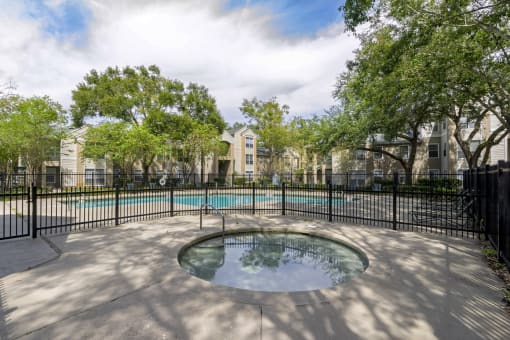 a hot tub sits in front of a pool with trees in the background
