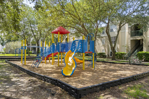 a playground with a yellow and blue slide and a red umbrella