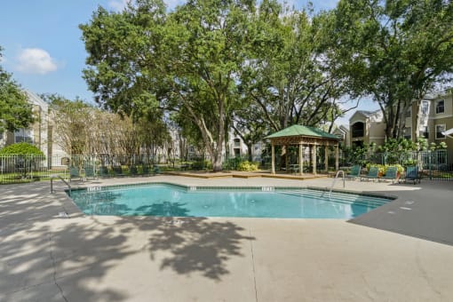 a swimming pool with a gazebo and trees in the background