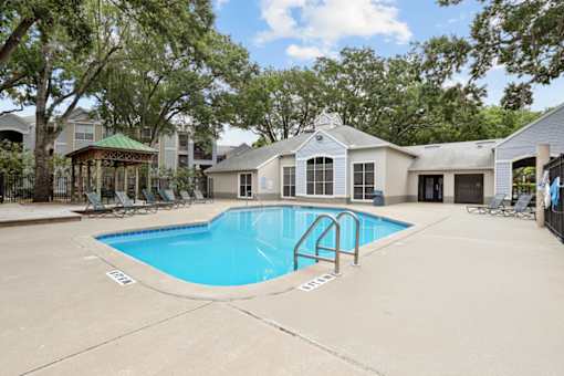 A swimming pool surrounded by trees and a gazebo.