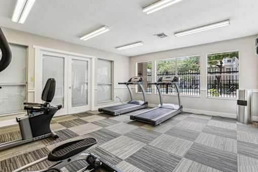 A gym with treadmills, elliptical machines, and a stationary bike.