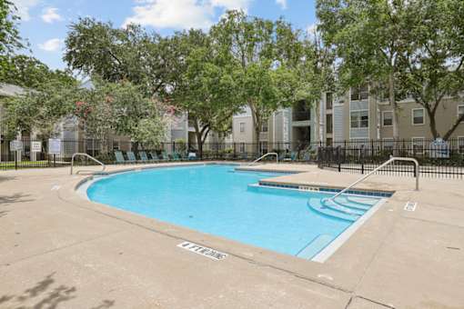 A small pool surrounded by a black fence and trees.