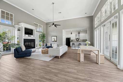 A spacious clubhouse lounge room with a fireplace and a dining area.