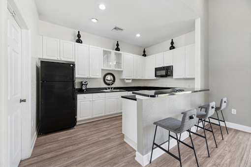 A clubhouse  kitchen with black appliances and white cabinets.