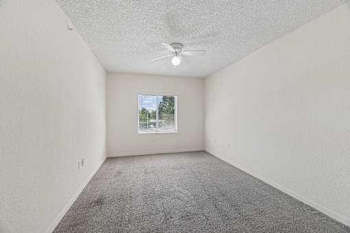 A bedroom with a ceiling fan and a window.