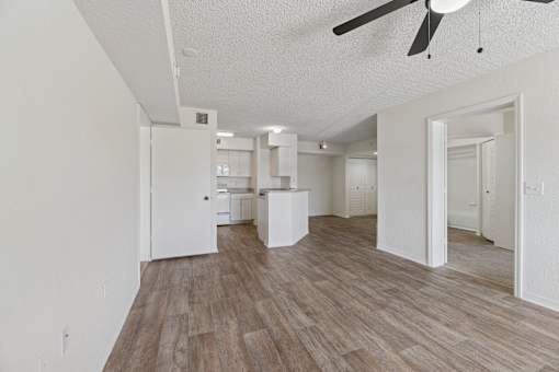 A living room with a ceiling fan and wooden flooring.