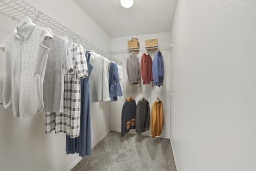 a walk in closet with white walls and a gray floor