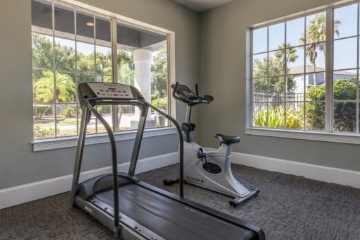 Fitness center with large windows featuring a treadmill and stationary bike.