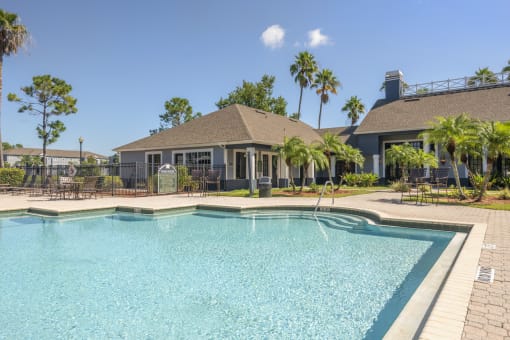 Swimming pool with clubhouse surrounded by palm trees
