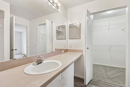 A bathroom with a sink, mirror, and shower.