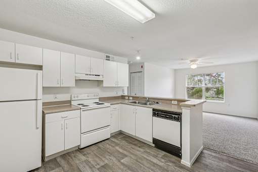 A white kitchen with wood flooring and white appliances.