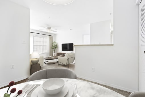 a living room with white walls and a white table with a white bowl on top of it
