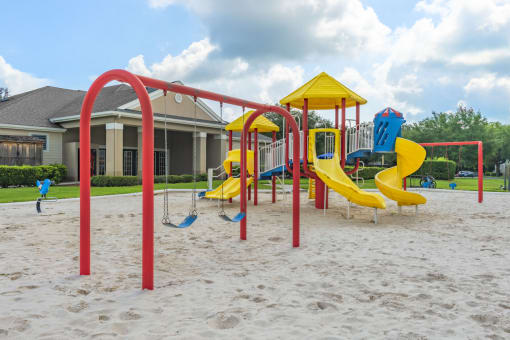 A red and yellow Playground with swing sets and slides.
