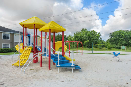 a playground with a yellow and red swing set and a blue and yellow slide