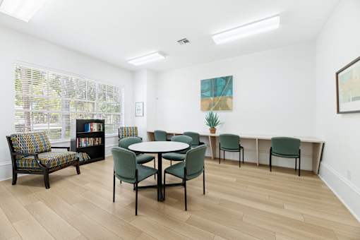 A room with a table and chairs and a painting on the wall.