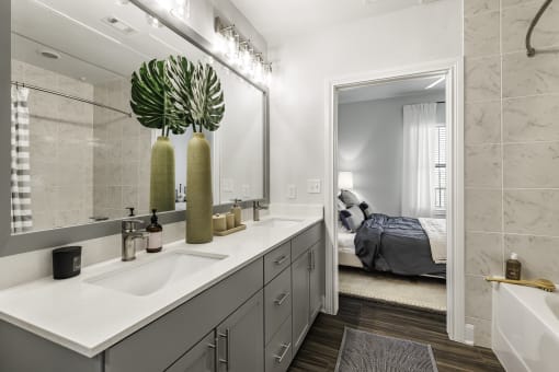 a bathroom with gray cabinets and a large mirror