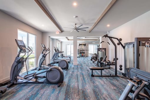 a gym with treadmills and other exercise equipment in a building with windows